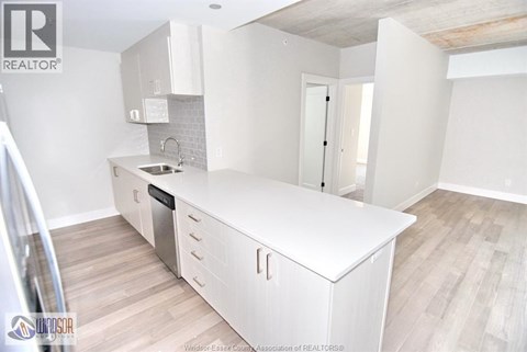 A kitchen with white cabinets and a wooden floor.