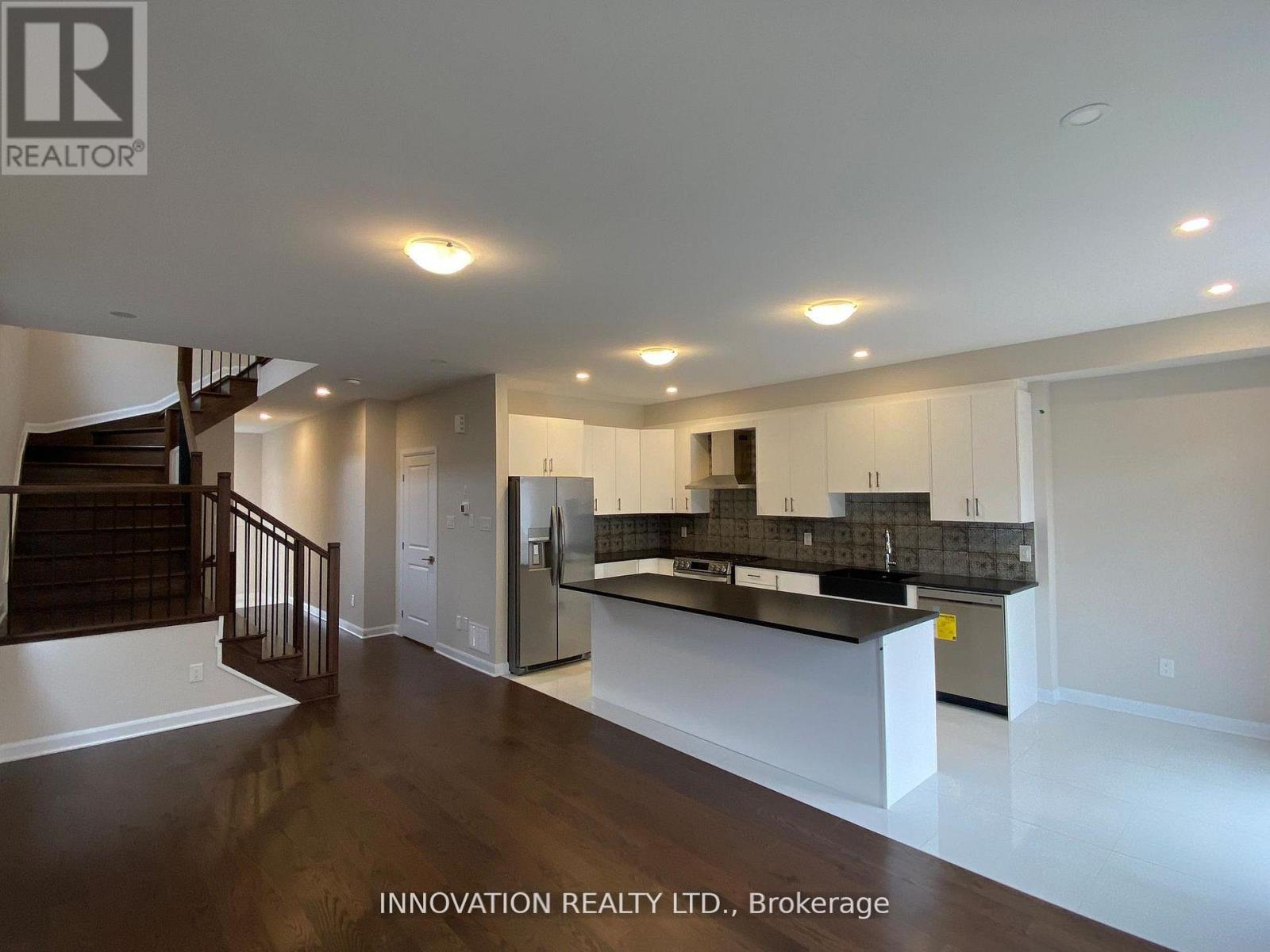 A spacious, well-lit room with a bar area and a staircase.