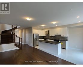 A spacious, well-lit room with a bar area and a staircase.