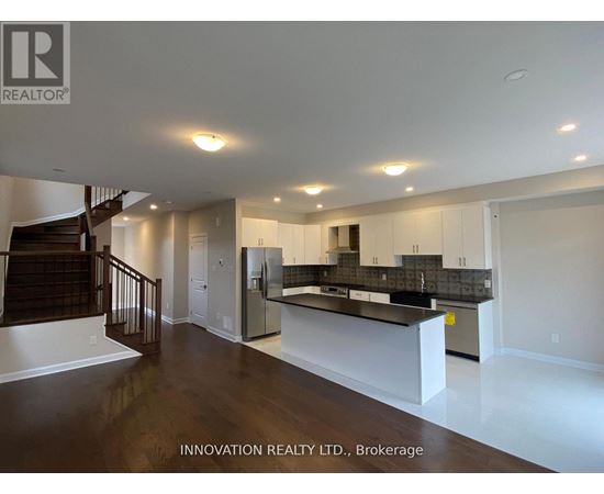 A spacious, well-lit room with a bar area and a staircase.