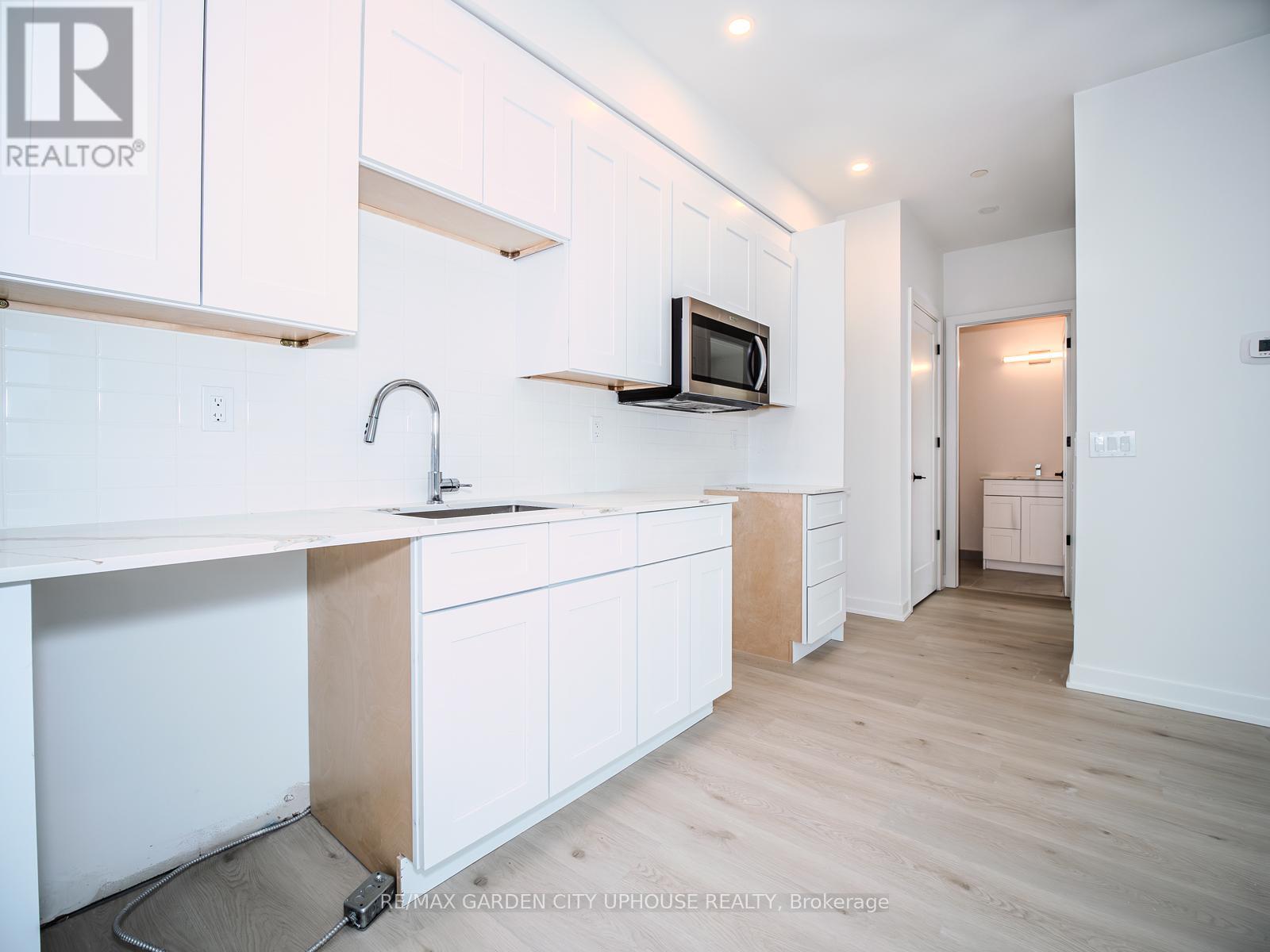 A kitchen with white cabinets and a microwave on the counter.