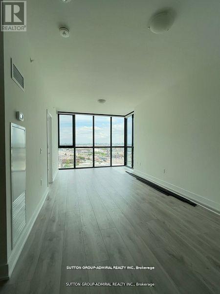 A spacious room with wood flooring and a large window overlooking the outdoors.