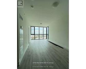 A spacious room with wood flooring and a large window overlooking the outdoors.