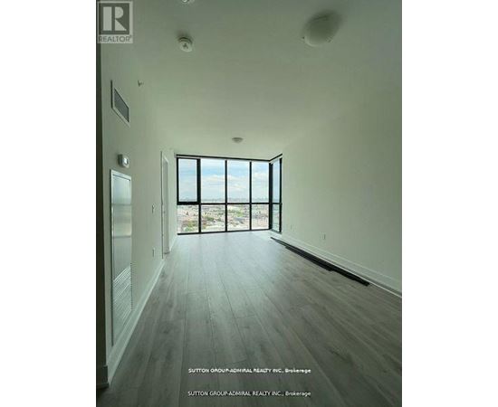 A spacious room with wood flooring and a large window overlooking the outdoors.