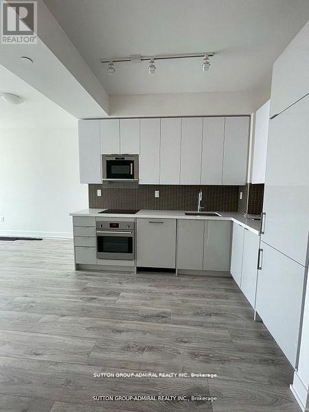A kitchen with white cabinets and a microwave on top of the oven.