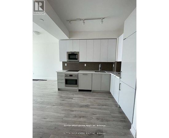 A kitchen with white cabinets and a microwave on top of the oven.