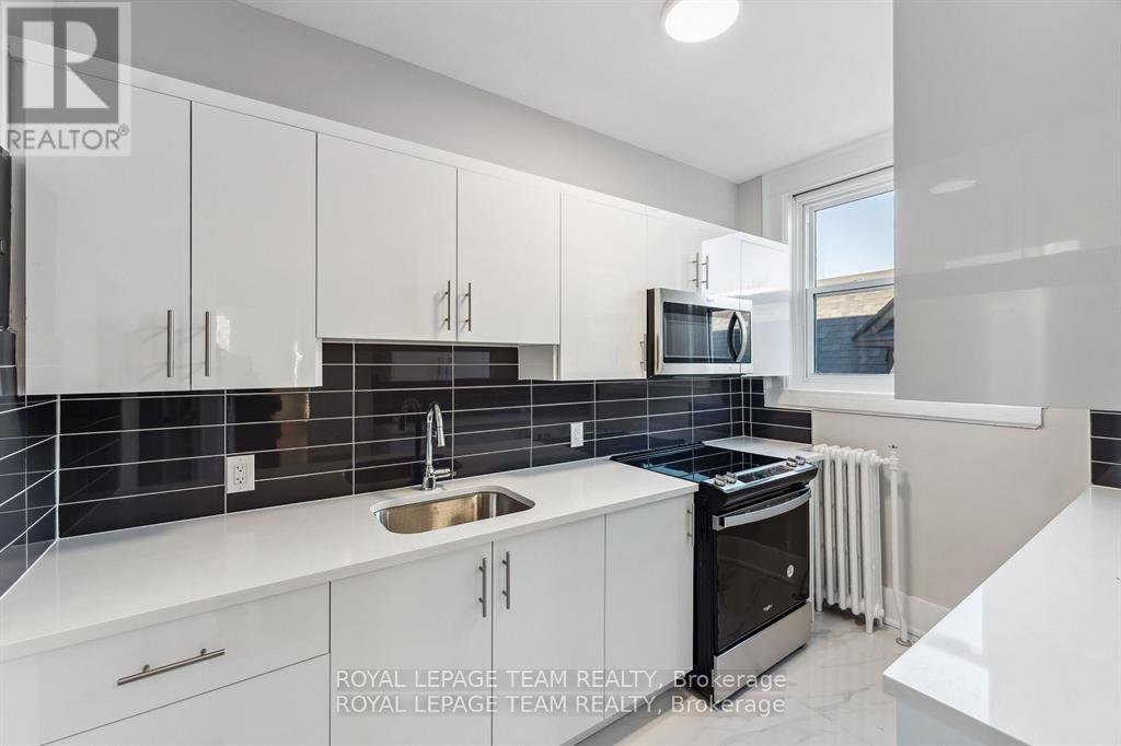 A modern kitchen with white cabinets and black appliances.