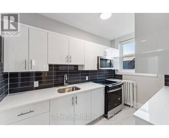 A modern kitchen with white cabinets and black appliances.