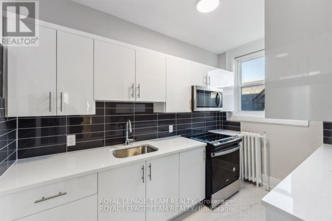 A modern kitchen with white cabinets and black appliances.