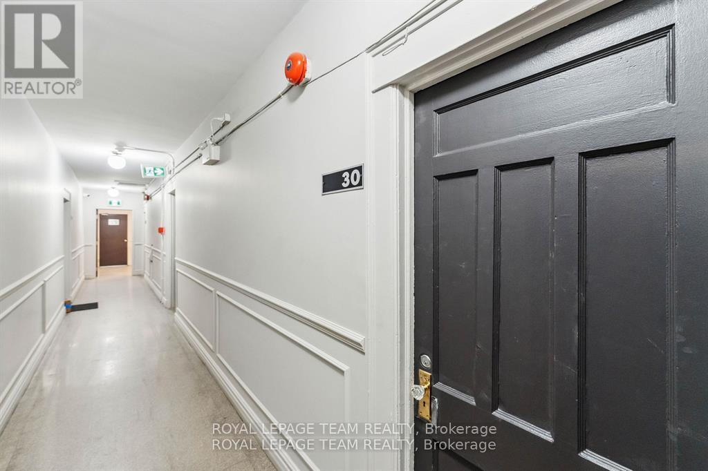 A hallway with a door on the right and a broom on the floor.