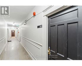 A hallway with a door on the right and a broom on the floor.