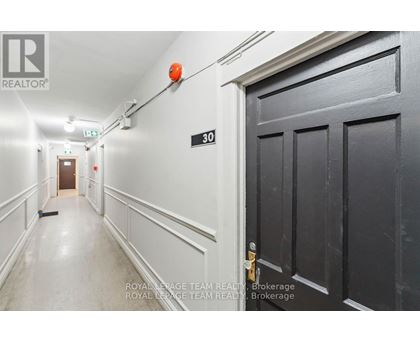 A hallway with a door on the right and a broom on the floor.
