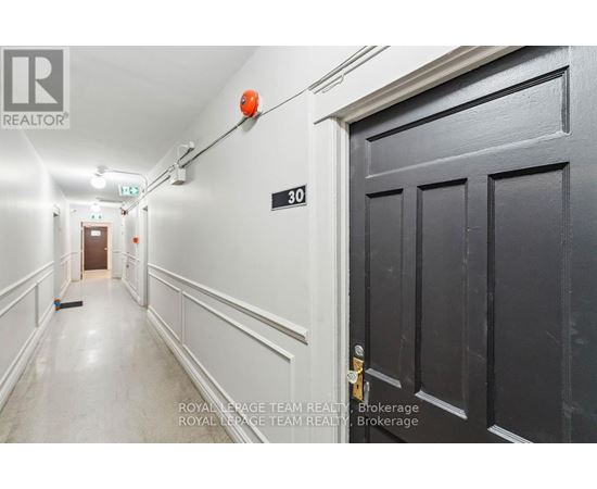 A hallway with a door on the right and a broom on the floor.