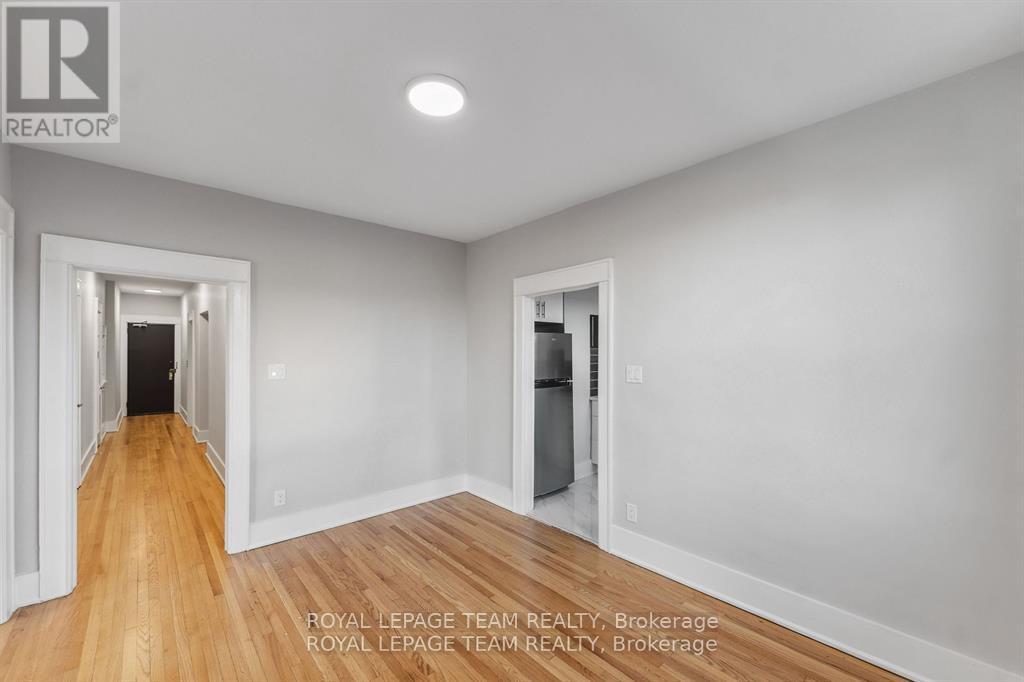 A spacious room with wooden floors and white walls, with a doorway leading to another room.