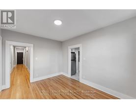 A spacious room with wooden floors and white walls, with a doorway leading to another room.