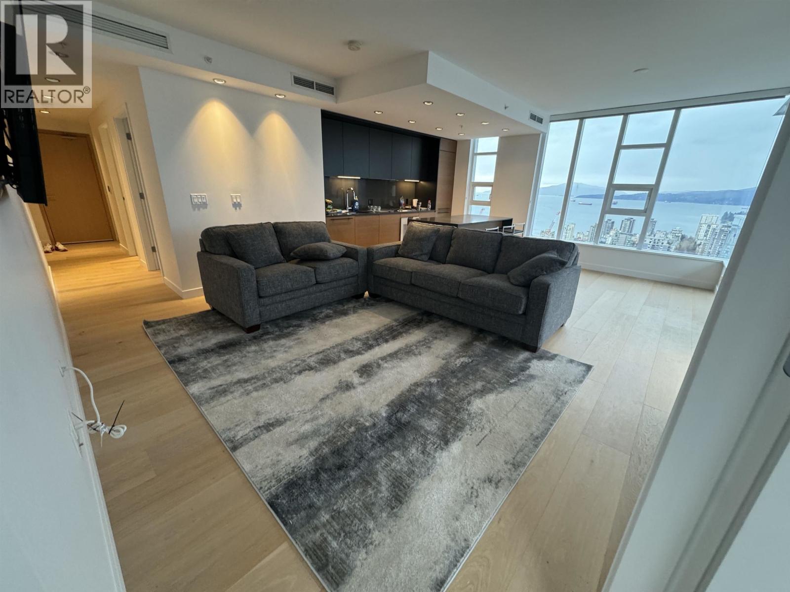 A living room with a large grey sofa and a rug in front of it.