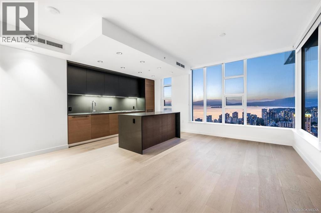 A spacious room with a bar area and a view of the cityscape through the windows.