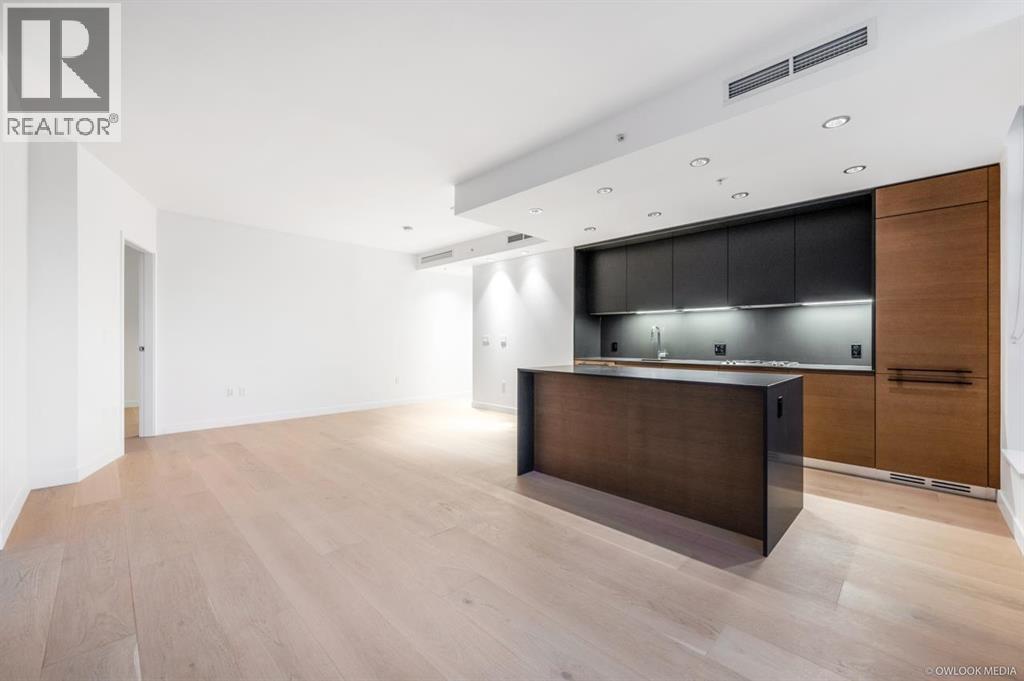 A modern kitchen with a dark brown island and wooden floors.