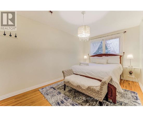 A bedroom with a bed, chair, and window.