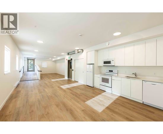 A well-lit kitchen with white cabinets and a wooden floor.