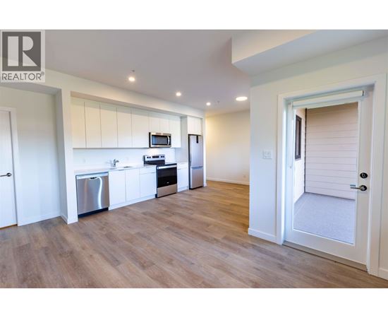 A kitchen with white cabinets and a wooden floor.
