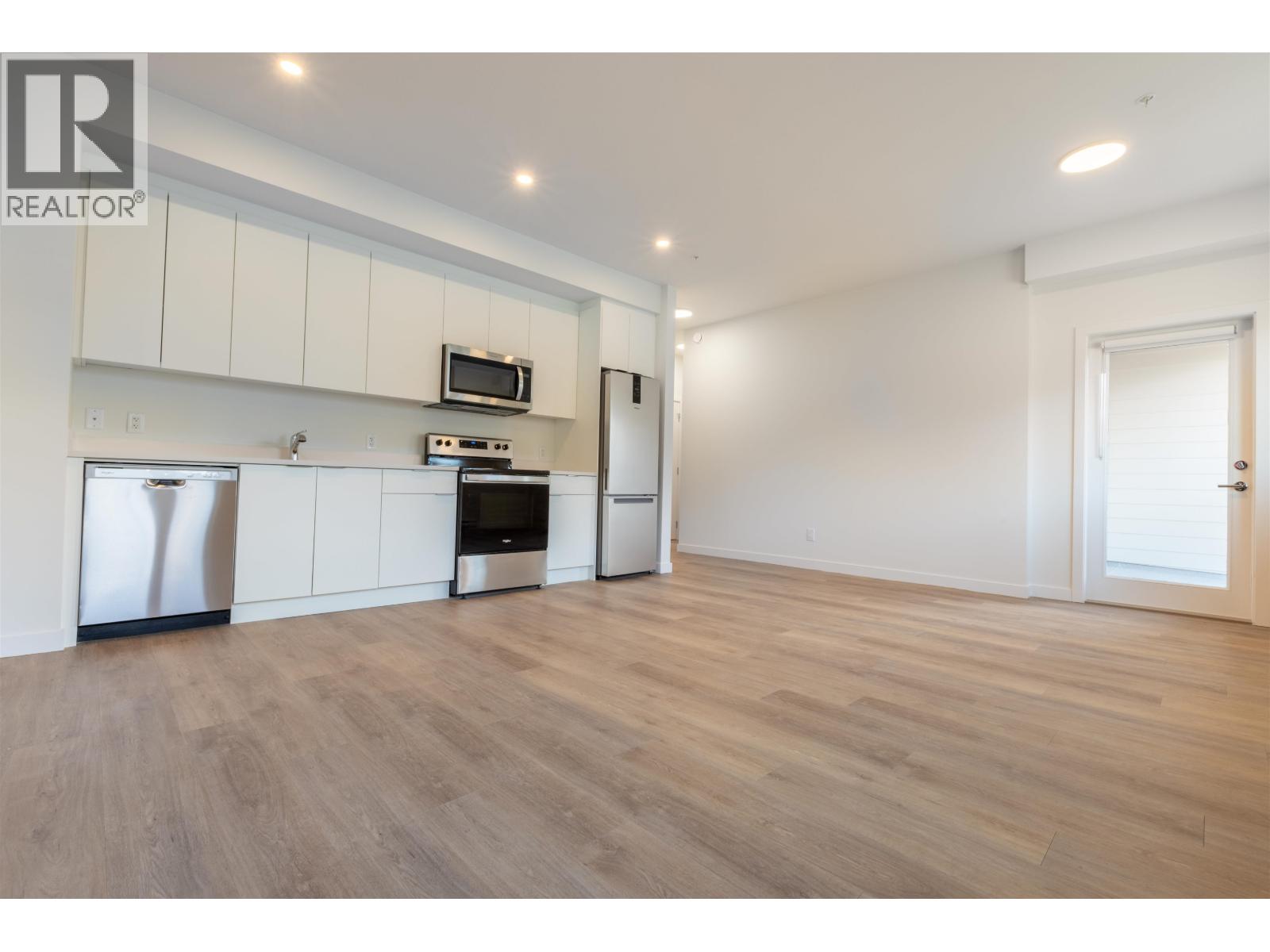 A kitchen with white cabinets and a wooden floor.