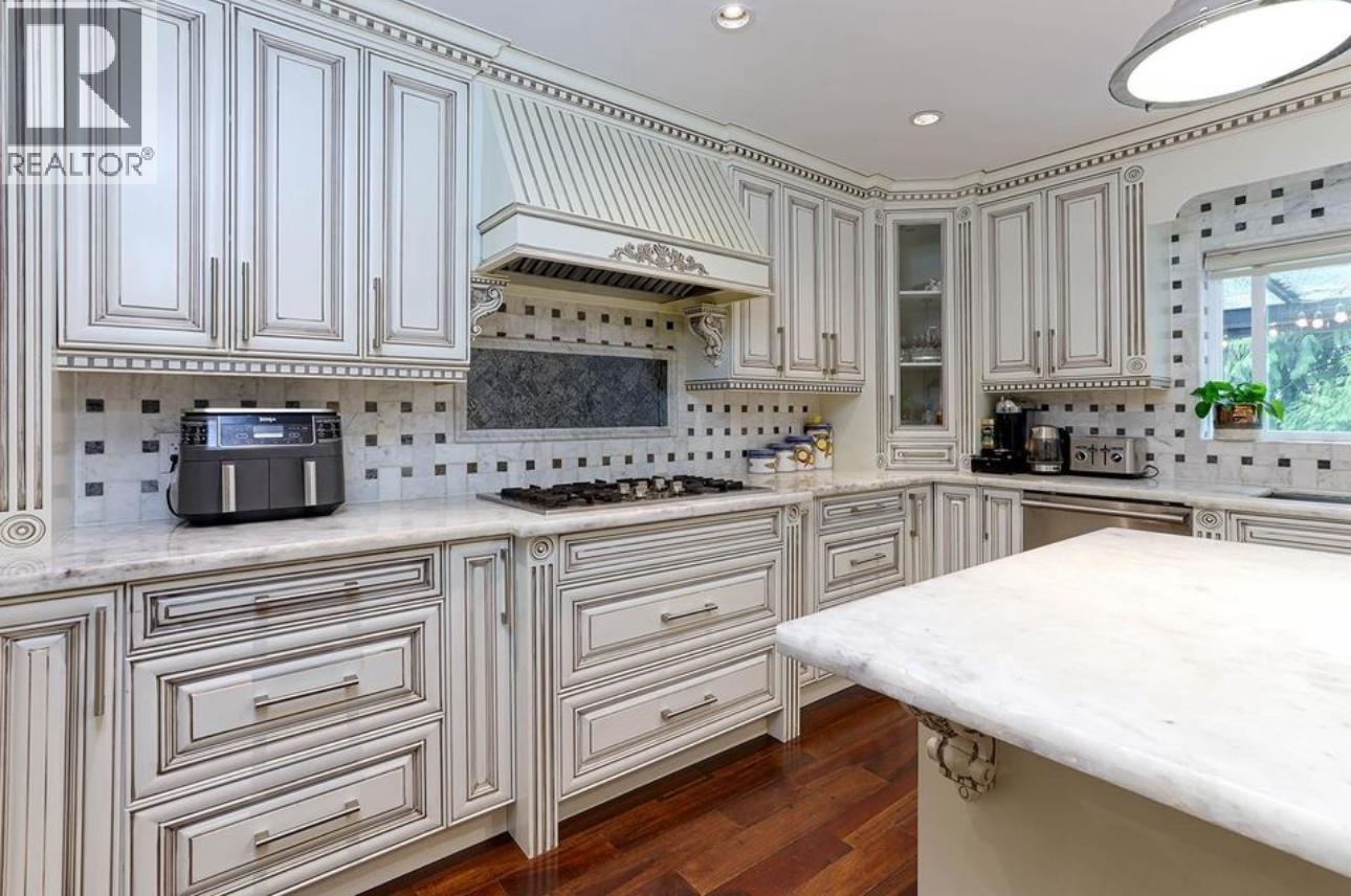 A kitchen with white cabinets and a marble countertop.