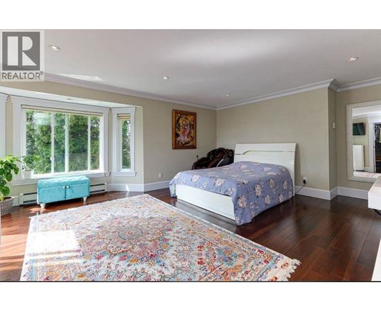 A bedroom with a large bed and a colorful rug.