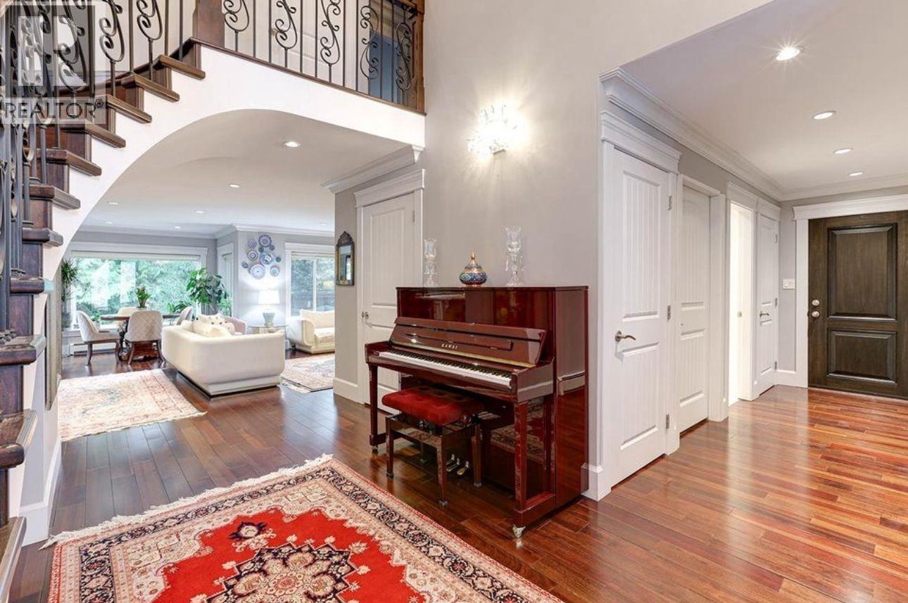 A grand piano sits in a spacious room with a staircase on the left.