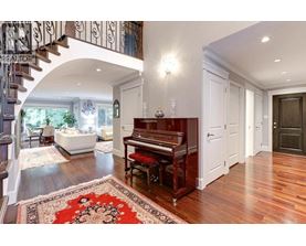 A grand piano sits in a spacious room with a staircase on the left.