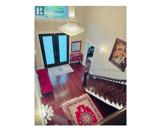 A living room with a red rug and a chandelier.