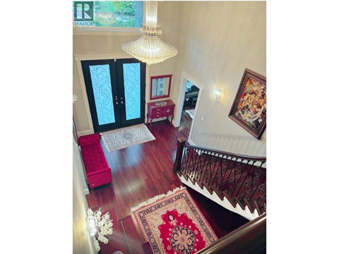 A living room with a red rug and a chandelier.