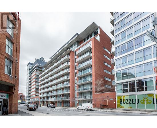 A street view of a city with a red brick building in the foreground and a modern glass building in the background.