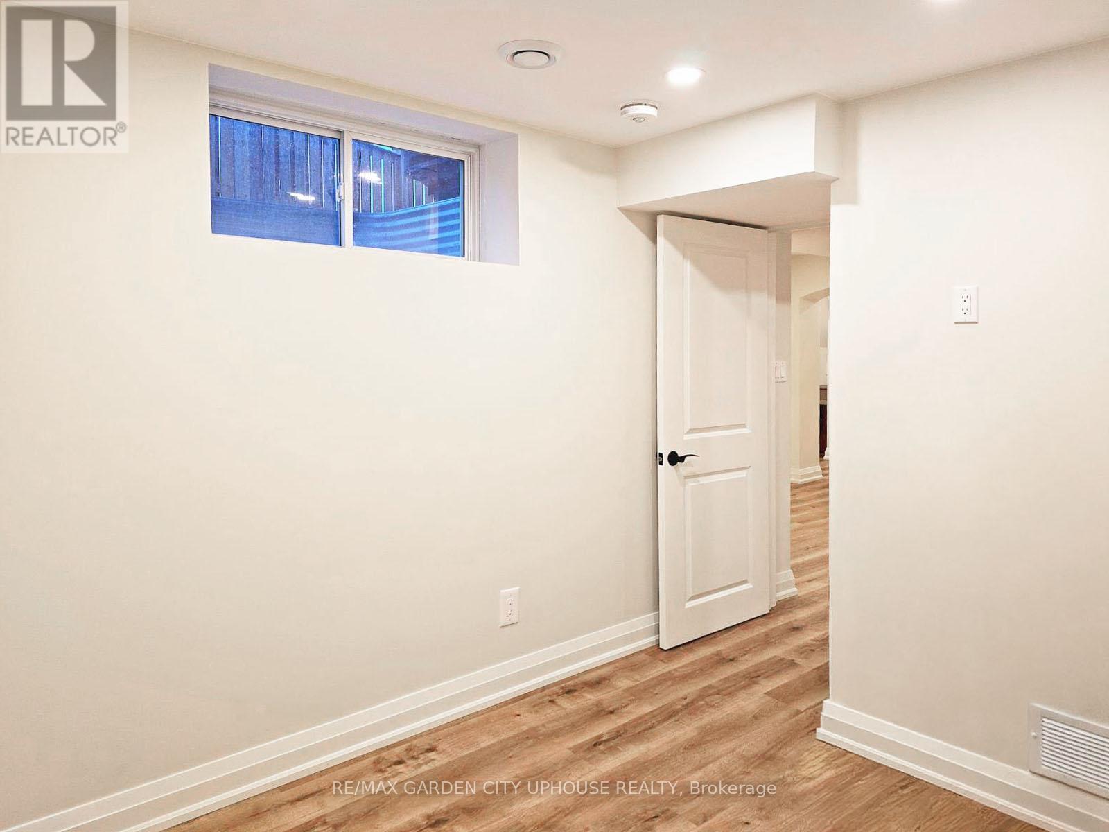 A room with a white door and a window with a view of a building outside.