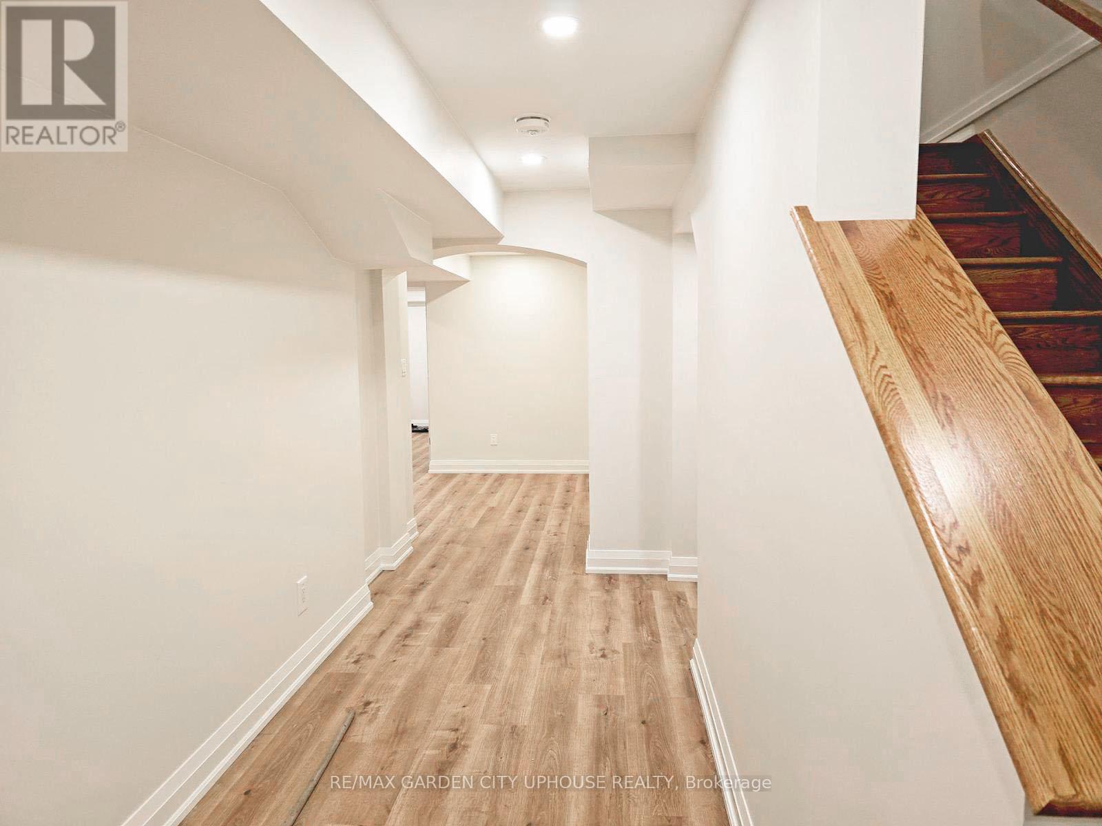 A hallway with wooden floors and a staircase on the right.