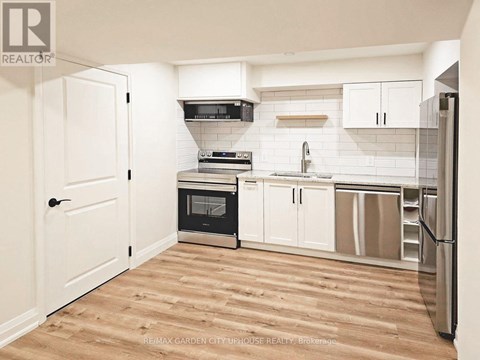 A kitchen with white cabinets and a wooden floor.