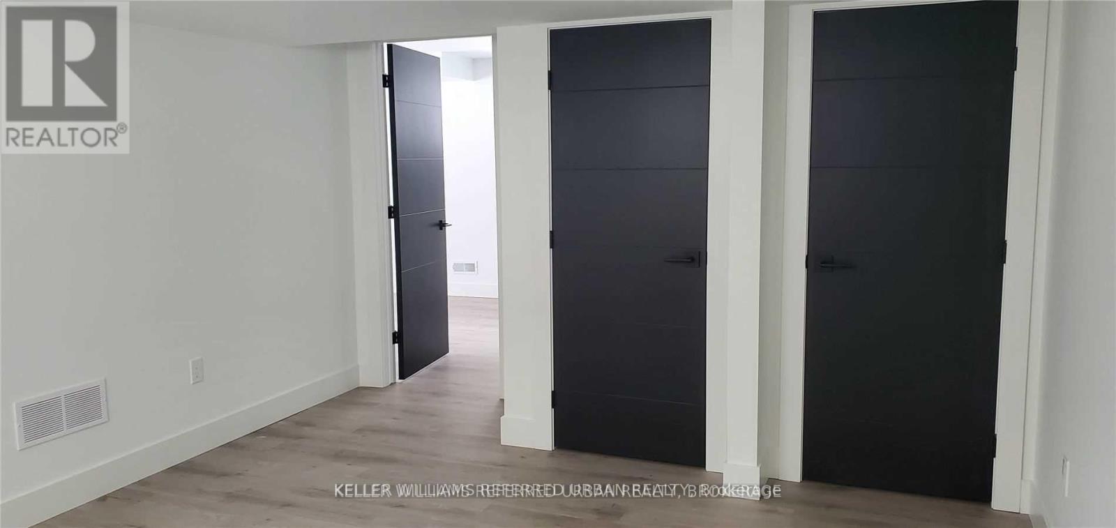 A room with a door on the left and a black door on the right.