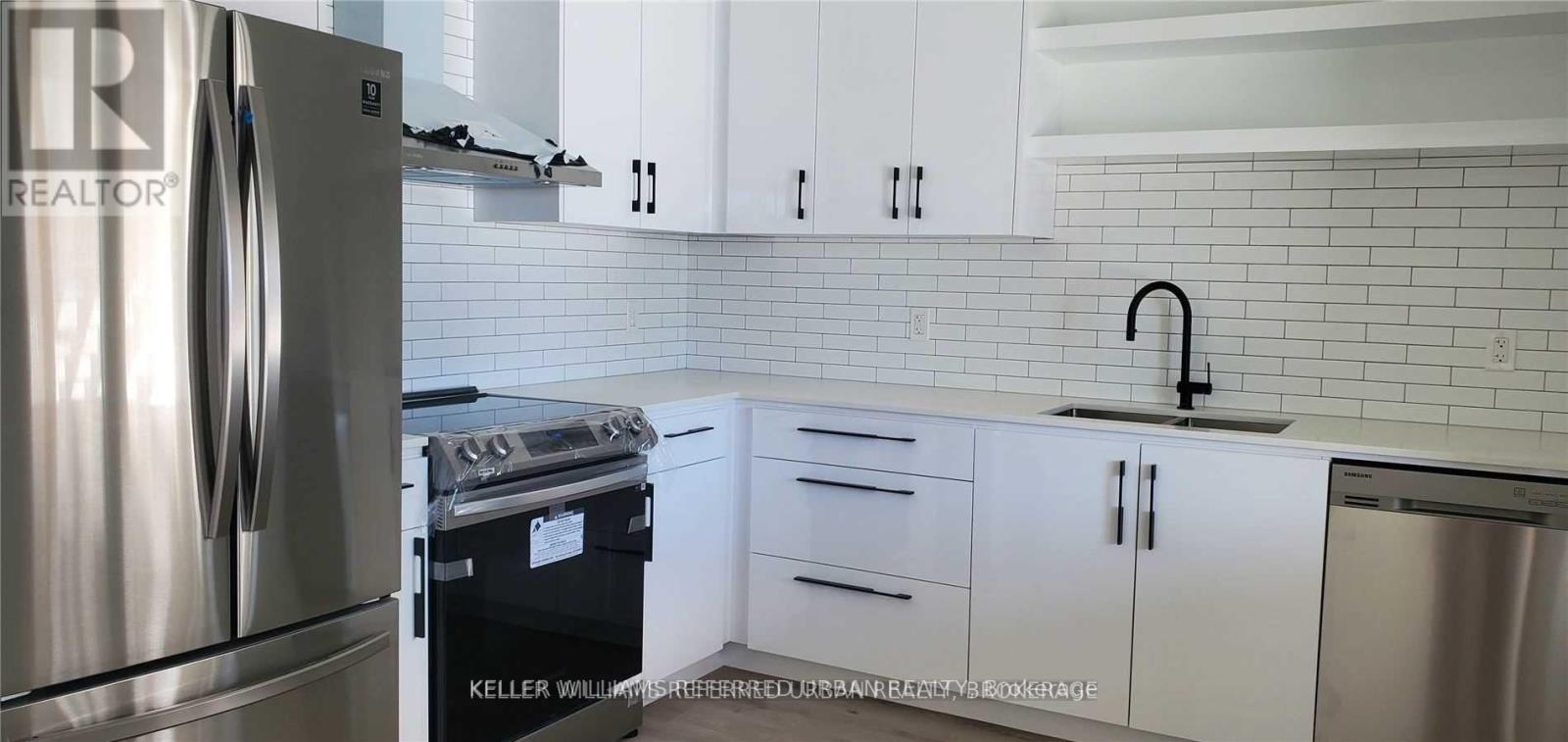 A kitchen with white cabinets and a stainless steel refrigerator.
