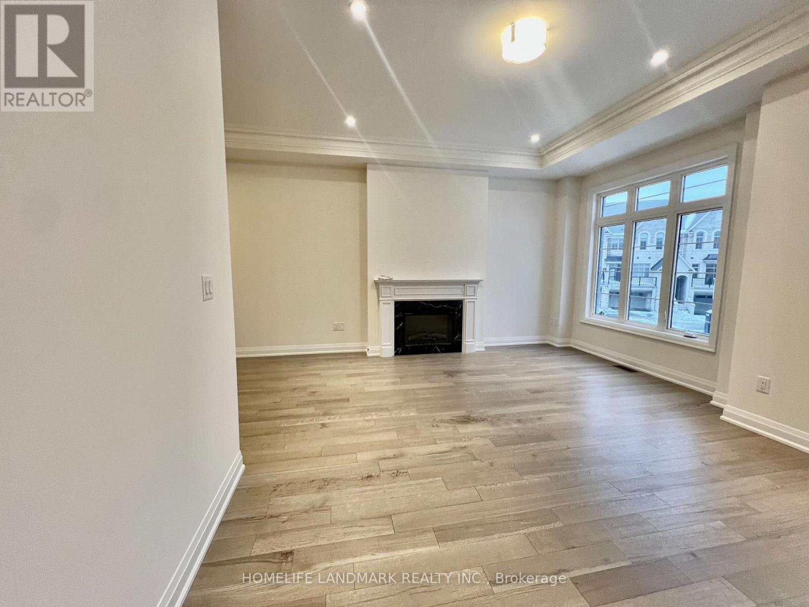 A spacious living room with a fireplace and wood flooring.