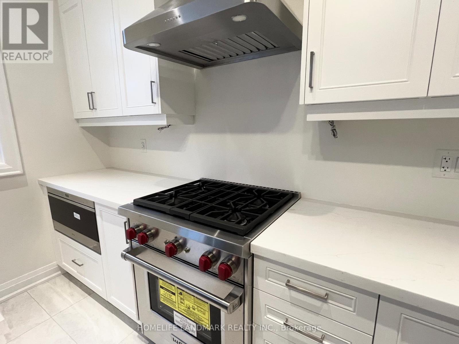 A modern kitchen with a stove top oven and white cabinets.