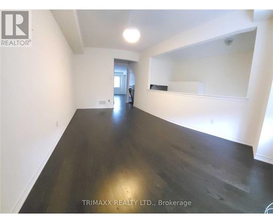 A spacious room with dark wood flooring and white walls, with a mirror on the wall.