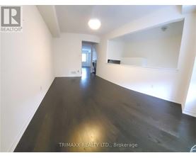 A spacious room with dark wood flooring and white walls, with a mirror on the wall.