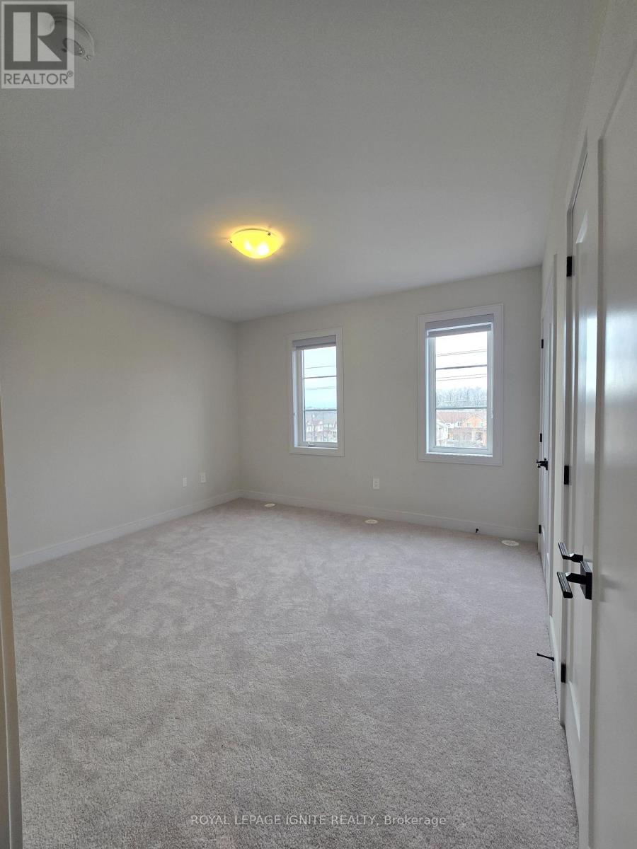 A white bedroom with a carpeted floor and a ceiling light.