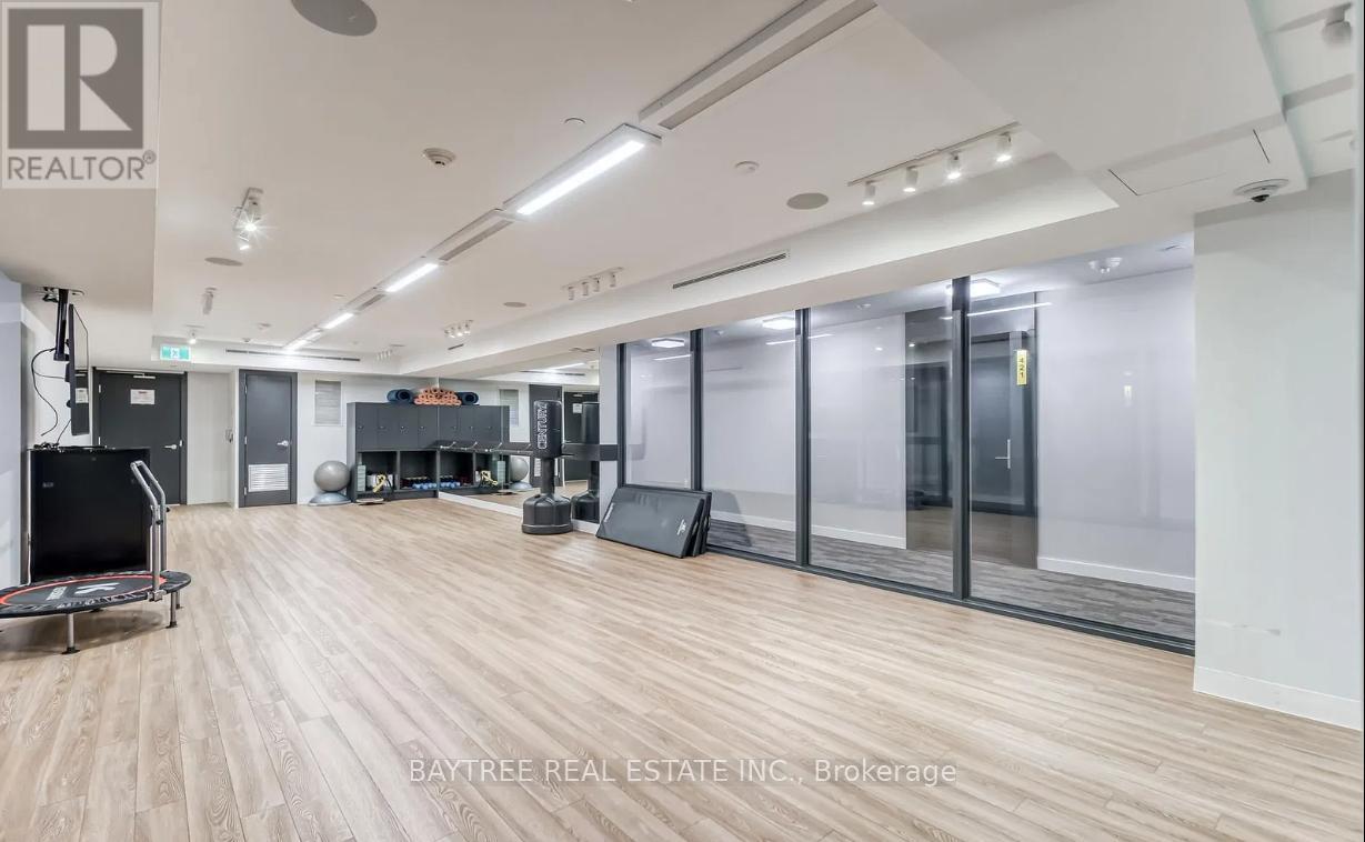 A spacious room with wooden flooring and a treadmill in the foreground.