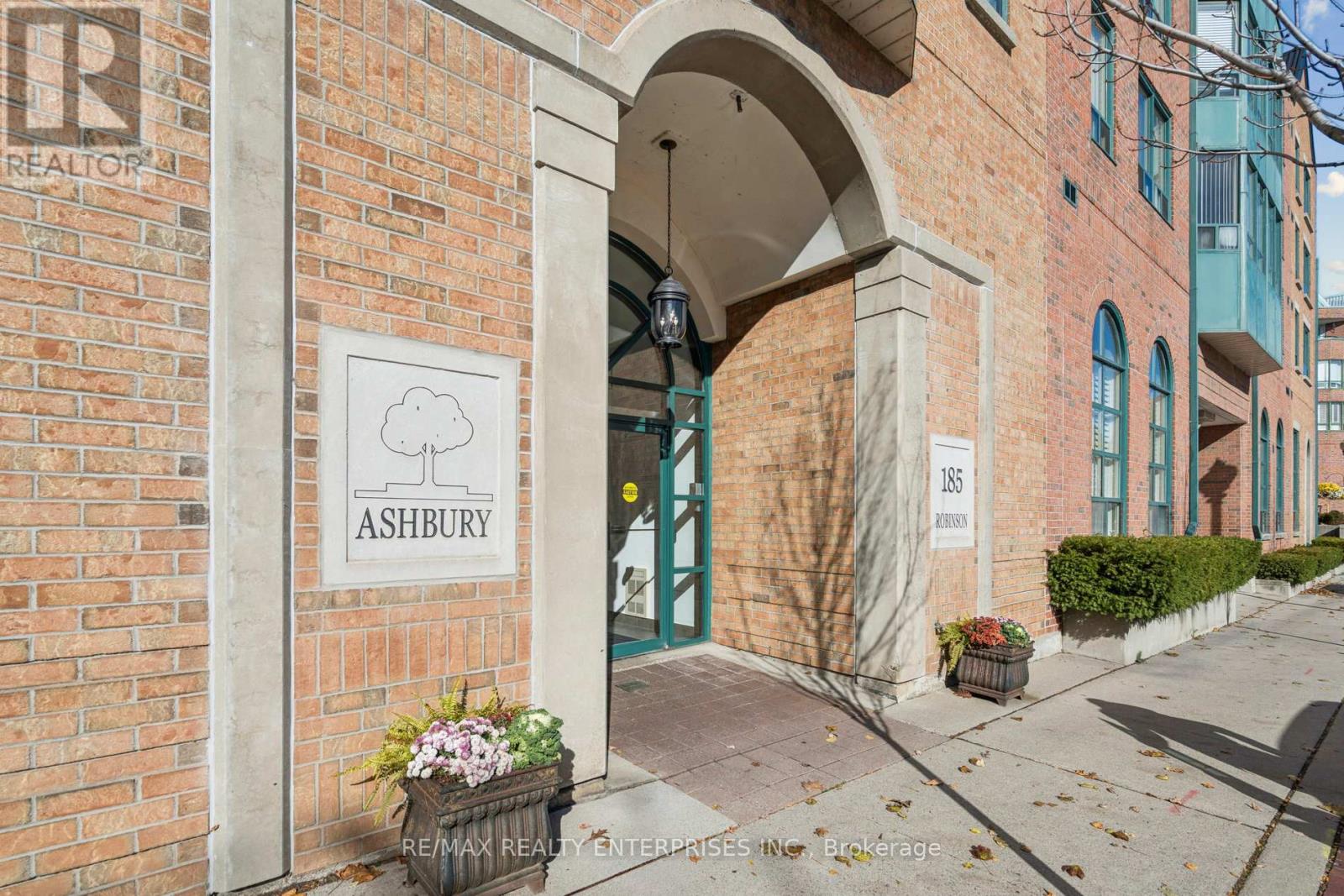 A sign for Ashbury RE/MAX Realty Enterprises is displayed on a brick building.