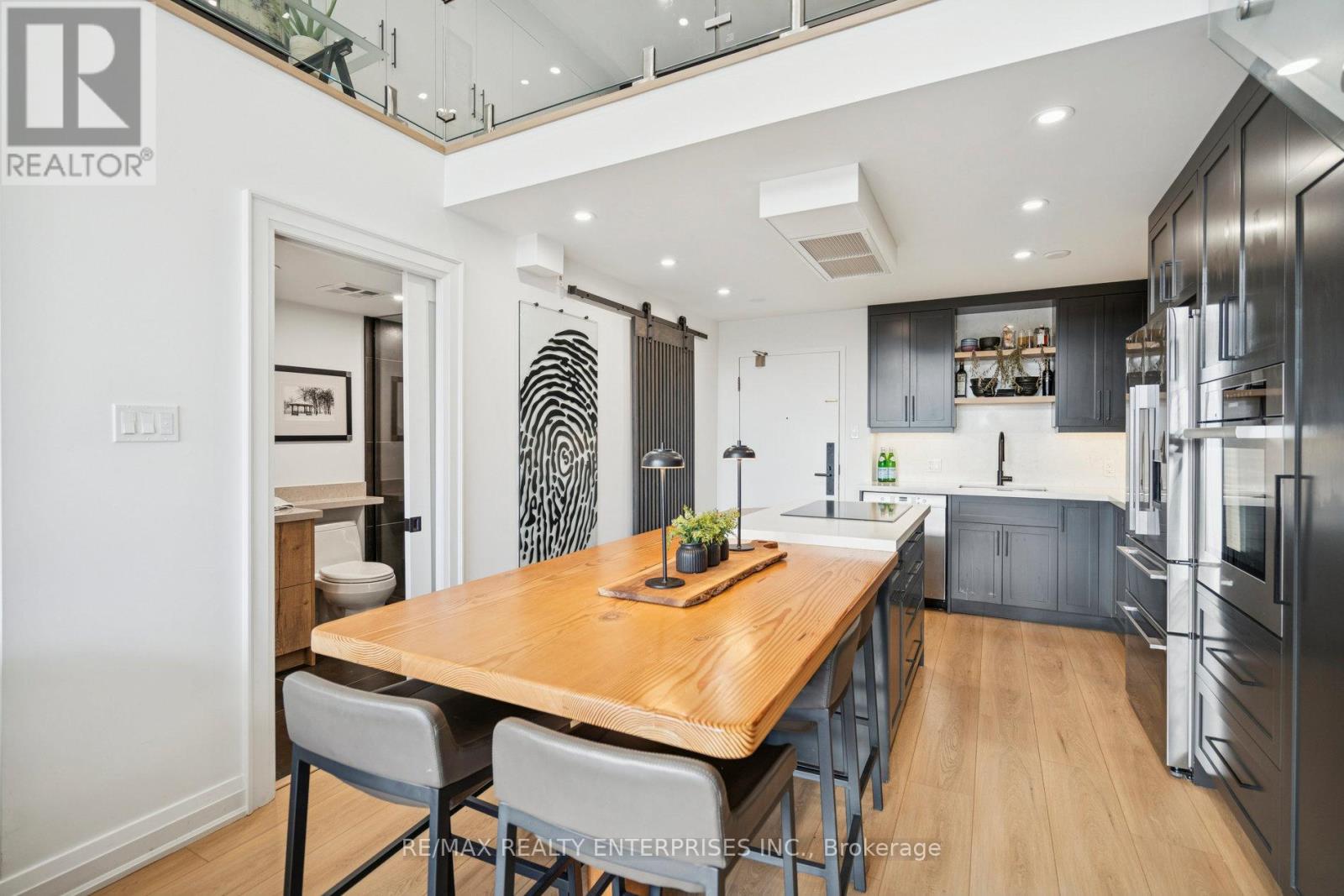 A modern kitchen with a wooden table and grey chairs.