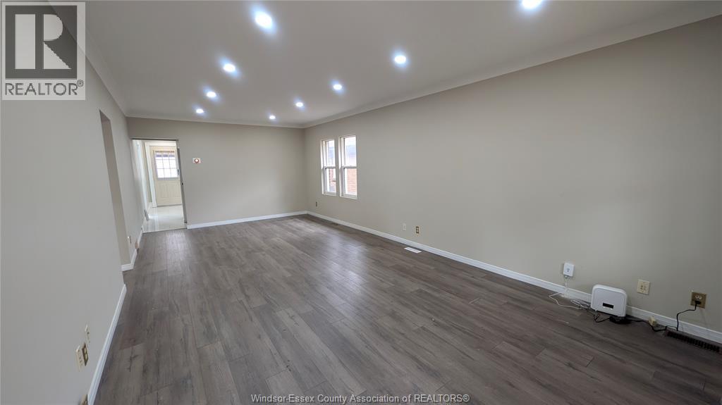 A spacious room with wooden flooring and recessed lighting.
