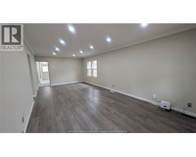 A spacious room with wooden flooring and recessed lighting.