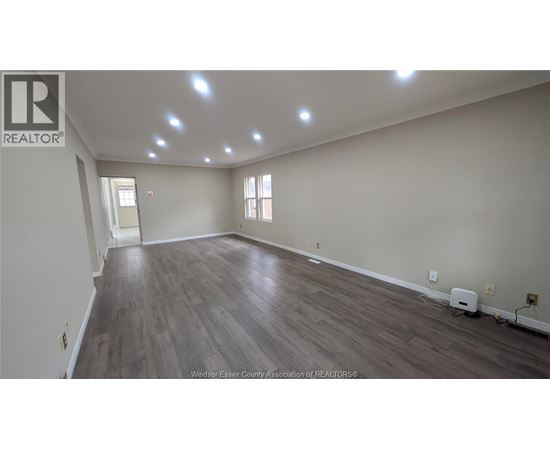 A spacious room with wooden flooring and recessed lighting.