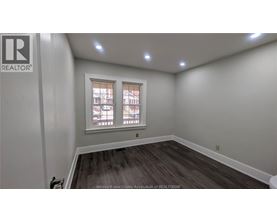 A room with a window and a wooden floor.
